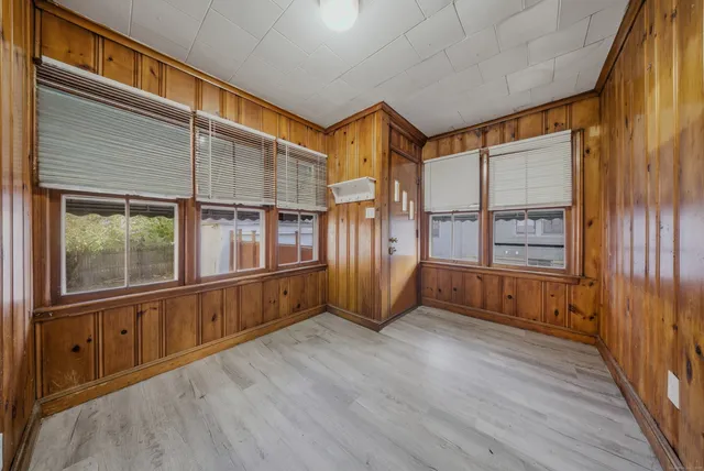 an empty room with wooden floor ceiling fan and windows