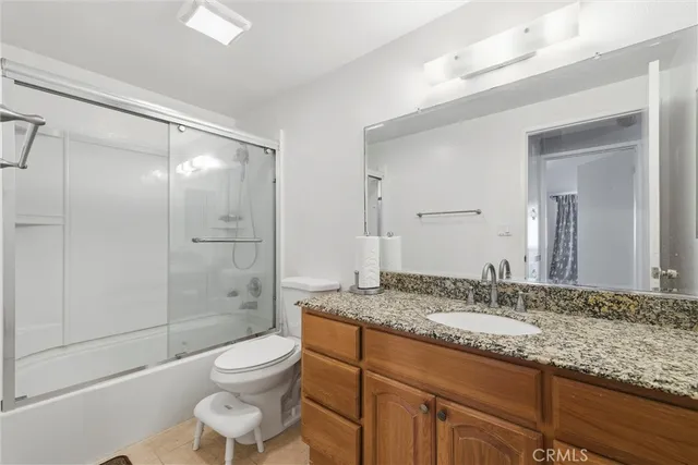 a bathroom with a granite countertop sink toilet a mirror and shower