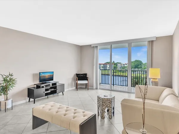 a living room with furniture a flat screen tv and a floor to ceiling window