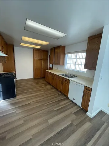 a large kitchen with wooden floor and stainless steel appliances