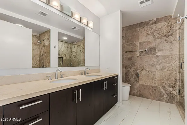 a bathroom with a double vanity sink mirror and shower