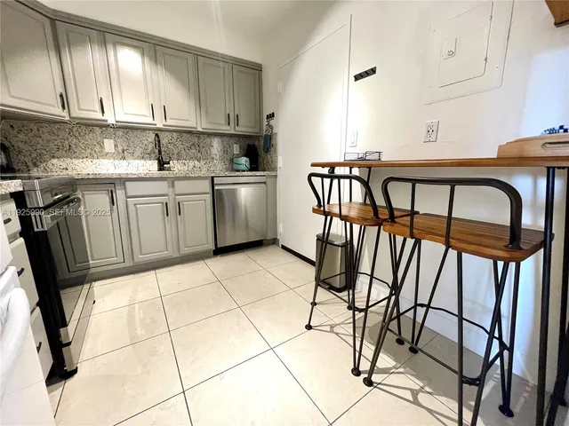 a kitchen with granite countertop a stove a refrigerator and white cabinets with wooden floor