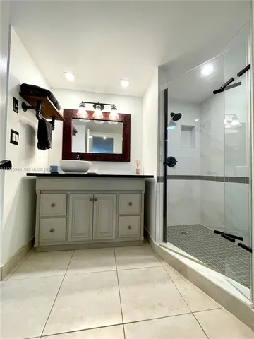 a bathroom with a granite countertop sink a mirror and shower