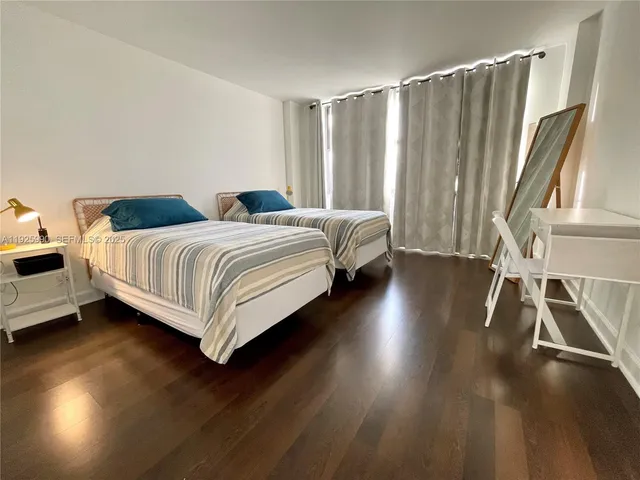 a spacious bedroom with a bed and wooden floor