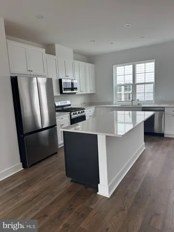 a kitchen with stainless steel appliances a refrigerator a stove a sink a center island and wooden floor