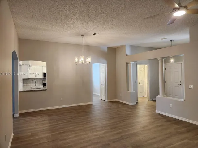 a view of a room with wooden floor and kitchen view