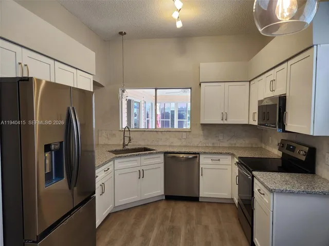 a kitchen with stainless steel appliances granite countertop a refrigerator a sink a stove a microwave and wooden cabinets