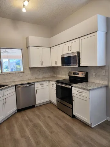 a kitchen with granite countertop white cabinets and stainless steel appliances