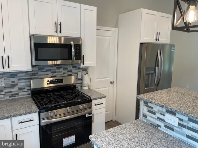 a kitchen with stainless steel appliances granite countertop a stove microwave and refrigerator