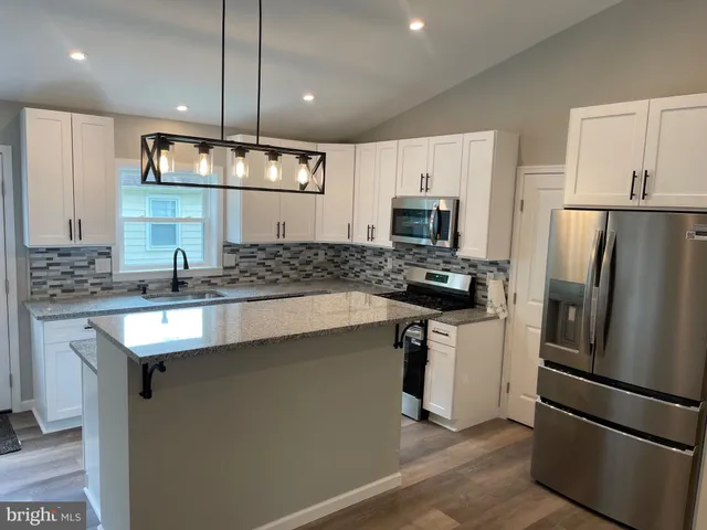 a kitchen with a sink stainless steel appliances a counter top space cabinets and a window
