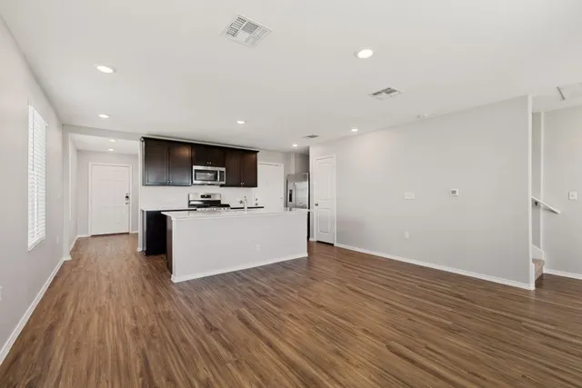 a view of kitchen with microwave oven stove and white cabinets with wooden floor