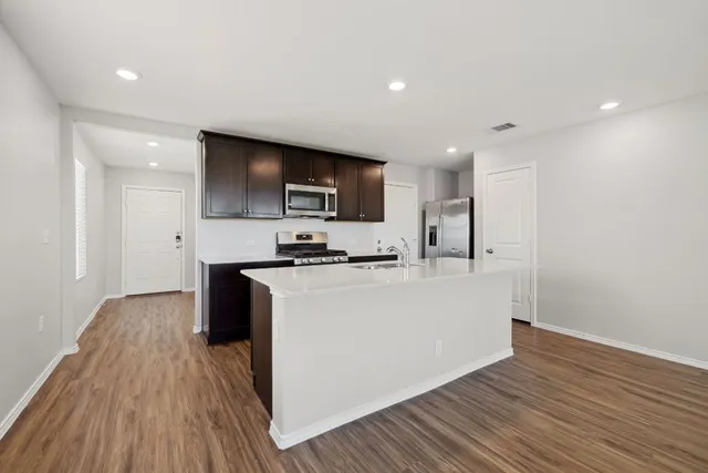a living room with stainless steel appliances furniture a refrigerator and a kitchen view