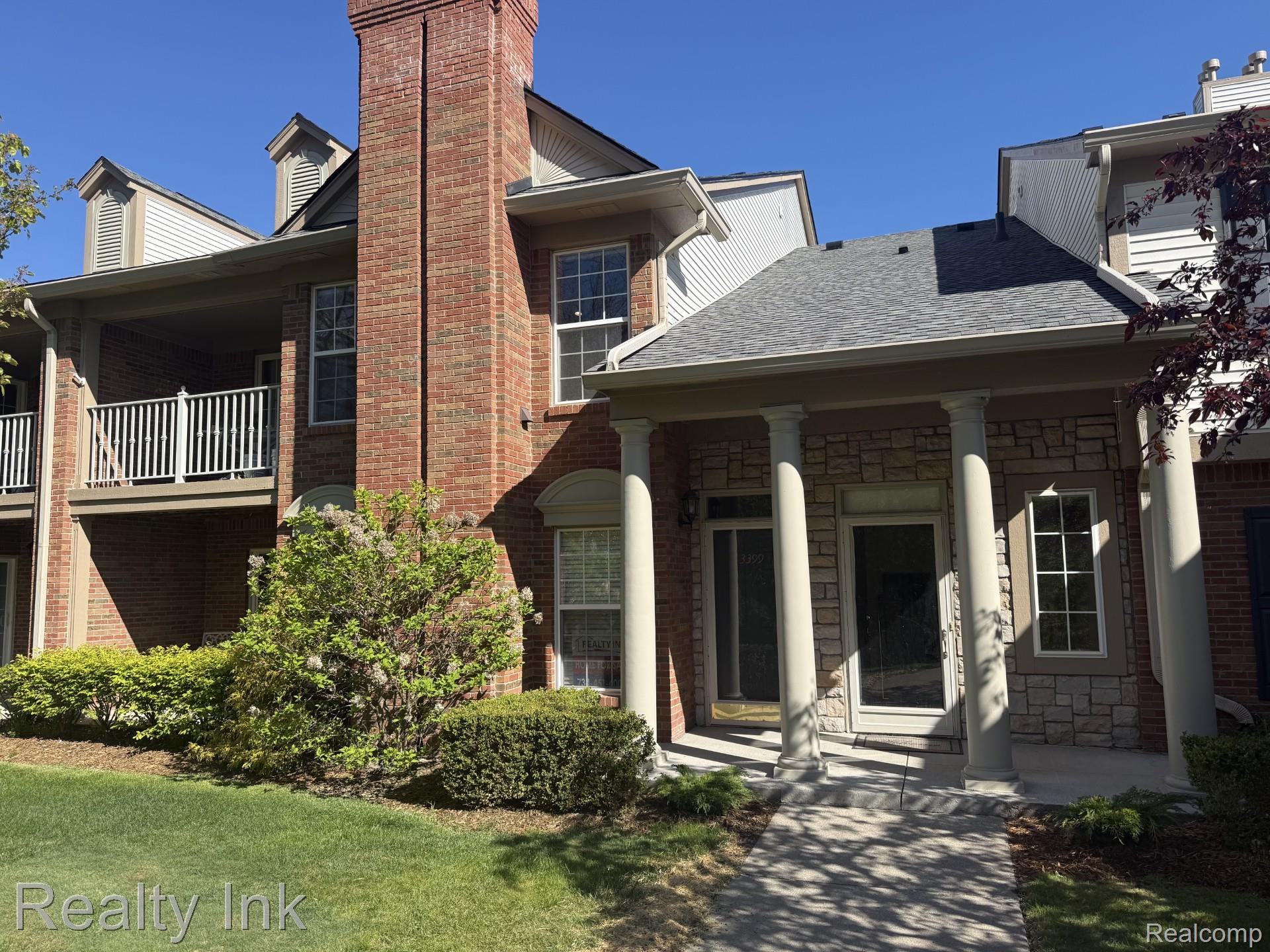 View of front of house featuring stone siding, a shingled roof, brick siding, and covered porch