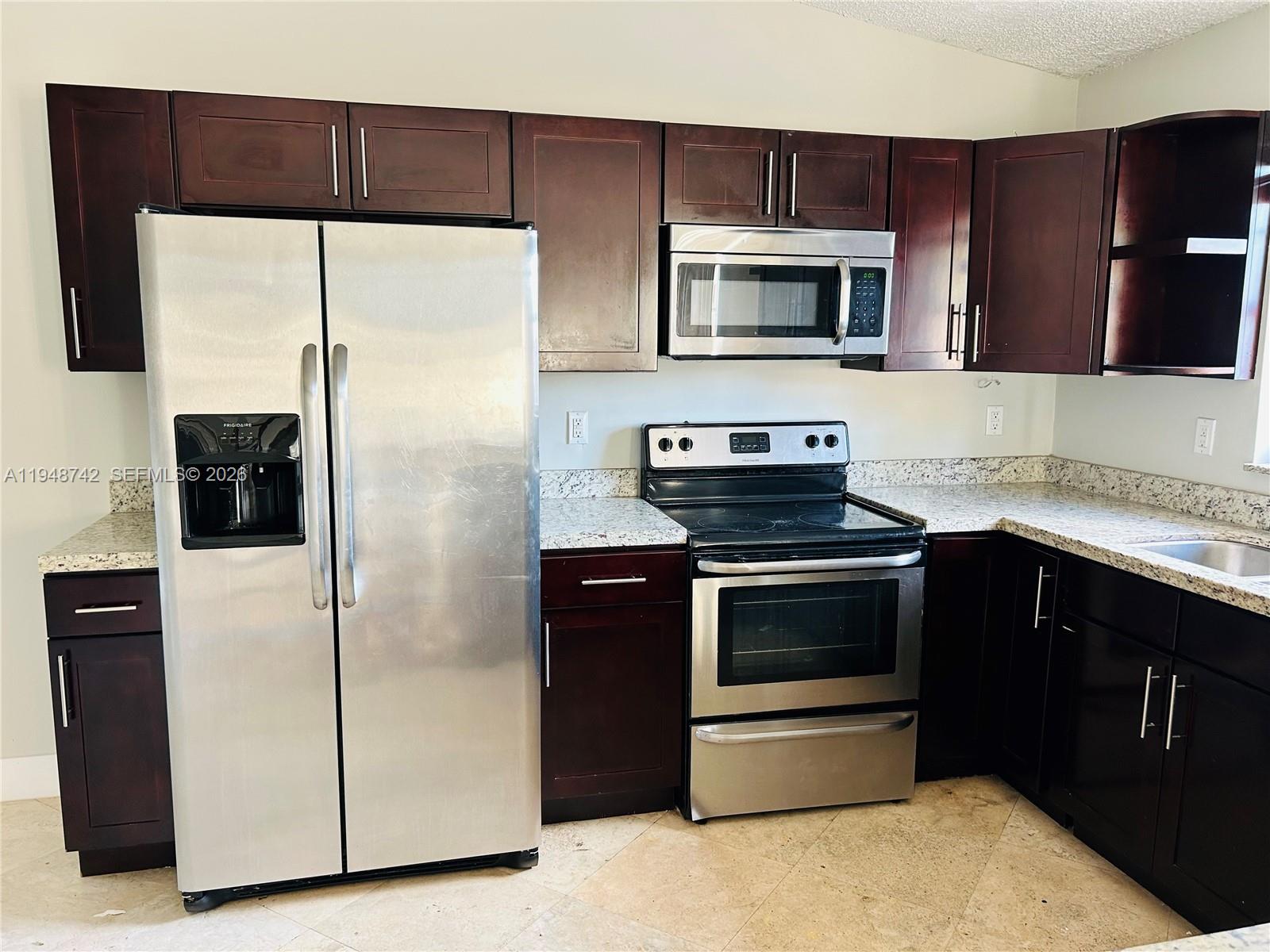 9752 Southwest 145th Place, Unit 9752 Miami, FL 33186 - Photo 3 of 17 a kitchen with a refrigerator stove and microwave