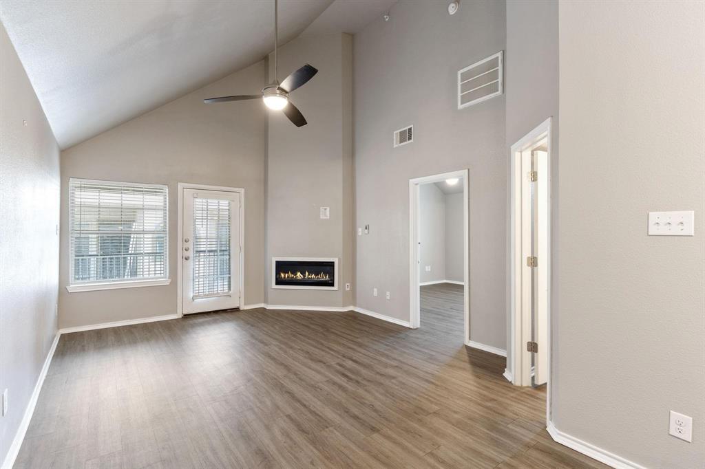 6108 Abrams Road, Unit 521 Dallas, TX 75231 - Photo 15 of 20 Spacious room featuring vaulted ceilings, wood-finish flooring, and a modern linear fireplace