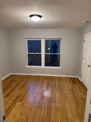 a view of an empty room with wooden floor and cabinet