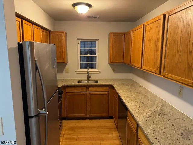 a kitchen with stainless steel appliances granite countertop a refrigerator a sink and dishwasher