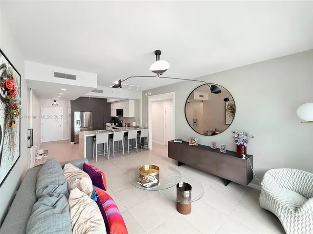 a living room with furniture a mirror and wooden floor