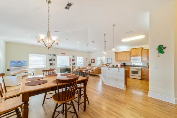 a view of a dining room and livingroom with furniture wooden floor a rug a painting and a chandelier