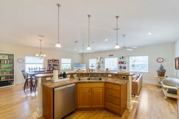 a kitchen with stainless steel appliances granite countertop a sink a stove a refrigerator cabinets and wooden floor