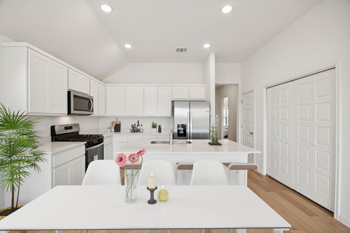 332 Bendecido Loop Elgin, TX 78621 - Photo 3 of 33 a kitchen with stainless steel appliances kitchen island granite countertop a stove a sink a refrigerator and white cabinets with wooden floor