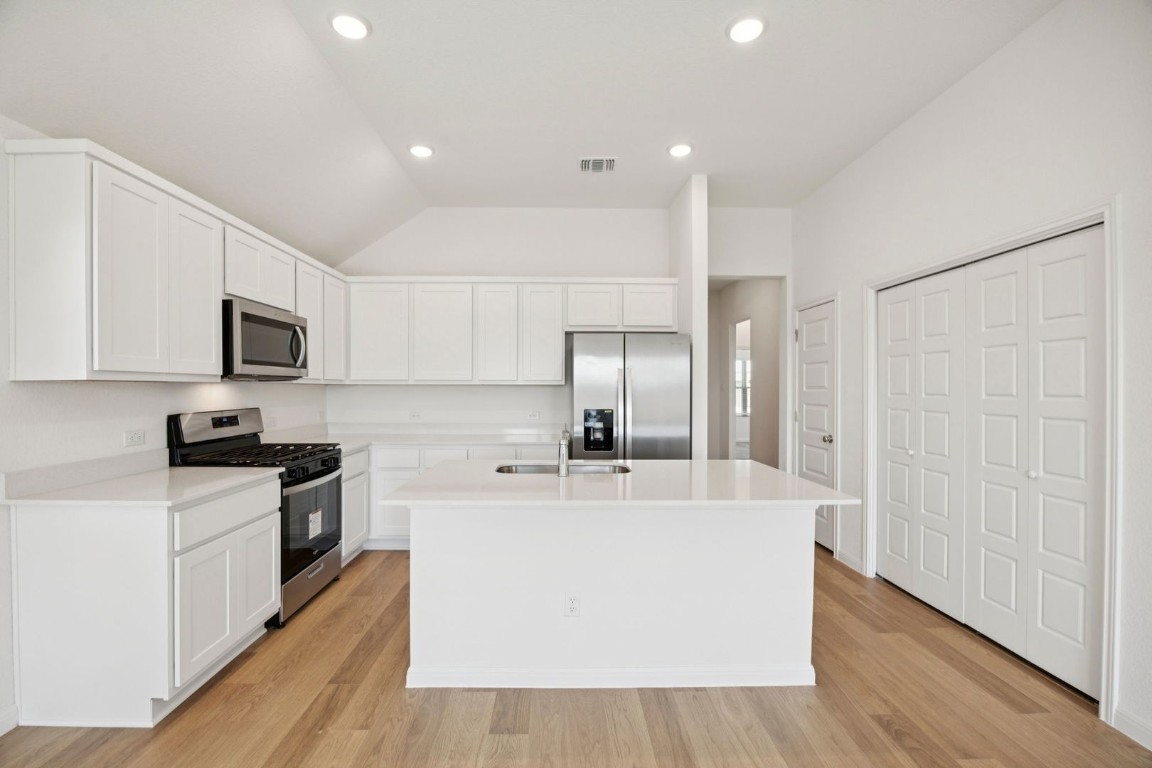 332 Bendecido Loop Elgin, TX 78621 - Photo 4 of 33 a large kitchen with stainless steel appliances a large counter top and a stove top oven
