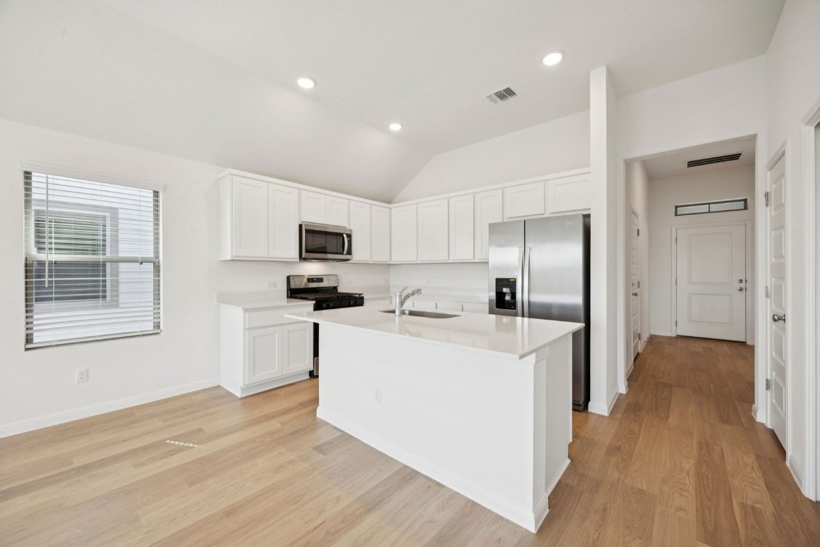 332 Bendecido Loop Elgin, TX 78621 - Photo 6 of 33 a kitchen with stainless steel appliances granite countertop a refrigerator oven a sink dishwasher and white cabinets with wooden floor