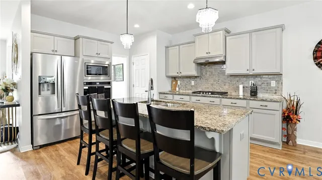 a large kitchen with stainless steel appliances granite countertop a lot of counter space and wooden floor