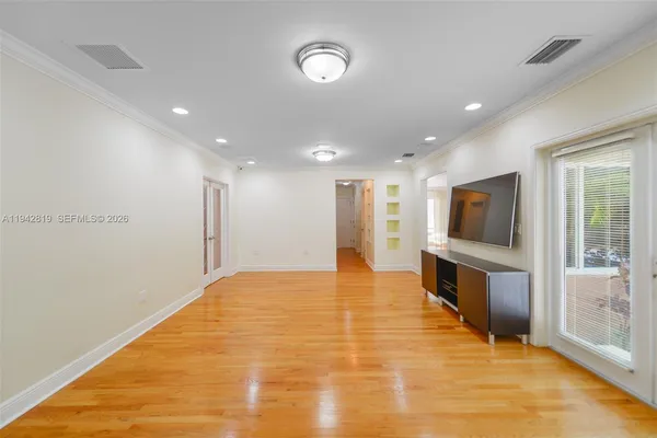 a view of an empty room with wooden floor and a window