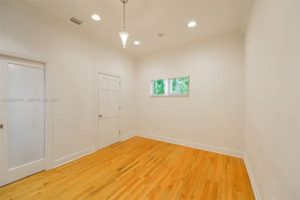 a view of an empty room with a window and wooden floor