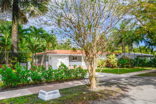 a view of a house with a yard and palm trees
