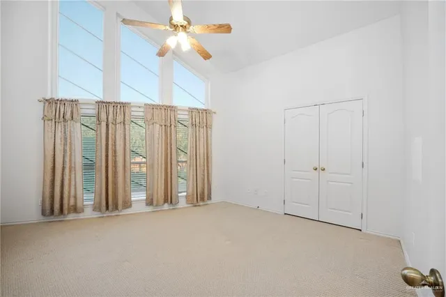 an empty room with windows and fan