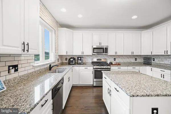 a kitchen with stainless steel appliances granite countertop a sink stove and cabinets
