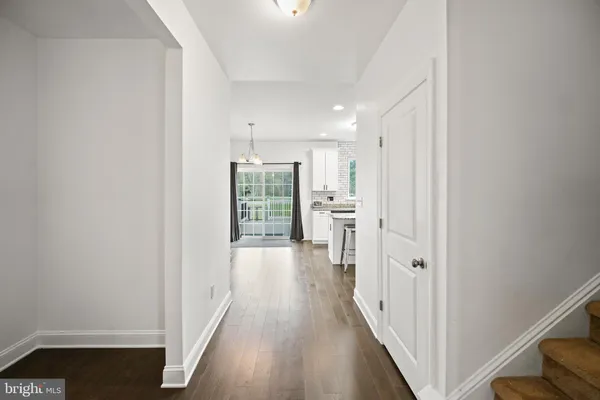 a view of a hallway with wooden floor and a living room