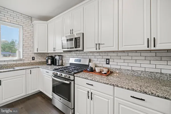 a kitchen with granite countertop white cabinets white appliances a granite counter tops and a wooden floors