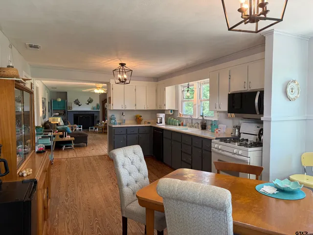 a large kitchen with stainless steel appliances granite countertop a stove a sink dishwasher a microwave oven with cabinets and wooden floor