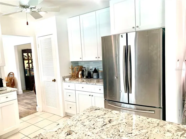 a backyard of a house with table and chairs floor to ceiling window and potted plants