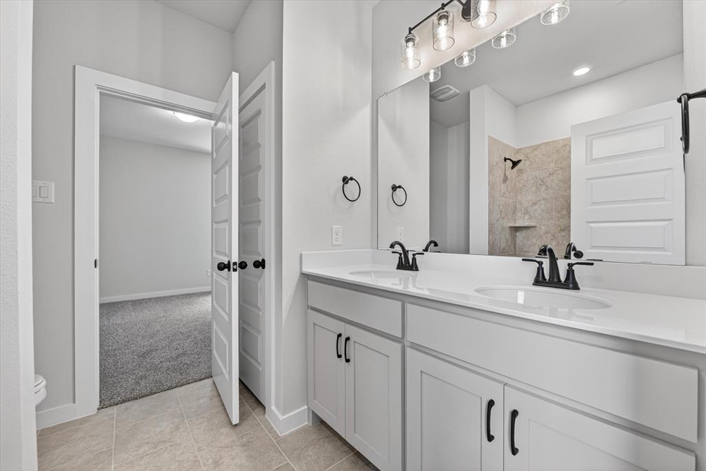 409 Mcalpine Springtown, TX 76082 - Photo 30 of 38 Dual vanity with white cabinetry, matte black fixtures, and a spacious mirror