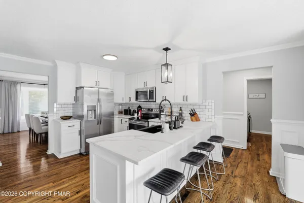 a kitchen with refrigerator and wooden floor