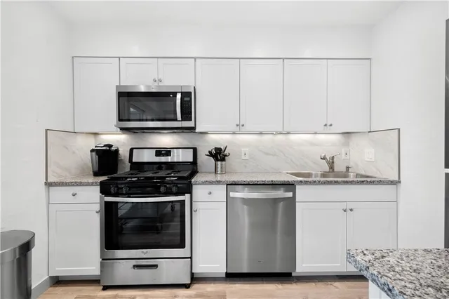 a kitchen with granite countertop a stove and a white cabinets