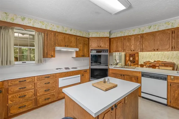a kitchen with stainless steel appliances kitchen island granite countertop a sink dishwasher stove and refrigerator with wooden cabinets