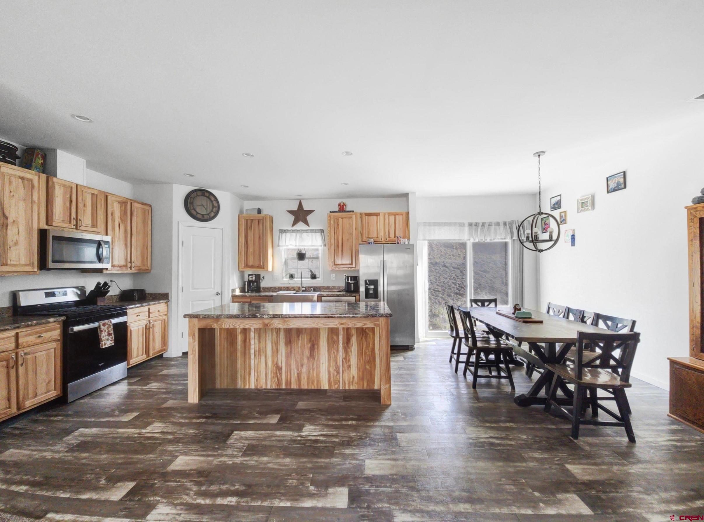28454 Lampshire Road Hotchkiss, CO 81419 - Photo 5 of 45 a kitchen with stainless steel appliances granite countertop a stove top oven a sink a dining table and chairs