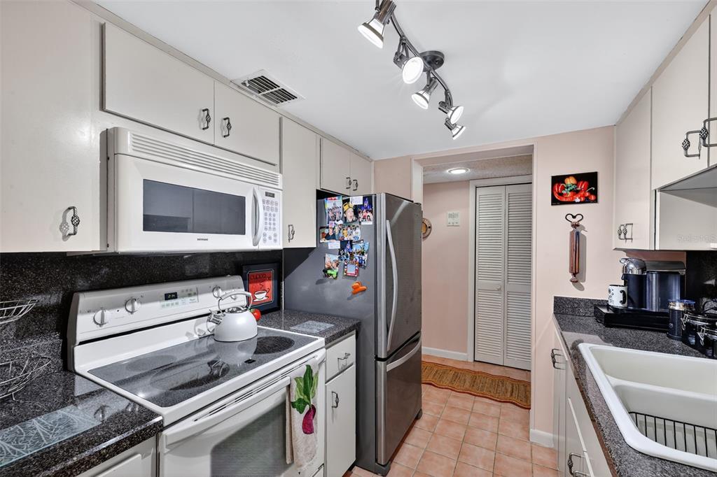 5541 Bay Boulevard, Unit 203 Port Richey, FL 34668 - Photo 13 of 30 a kitchen with stainless steel appliances granite countertop a stove and a refrigerator