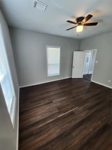 a view of an empty room with a window and wooden floor