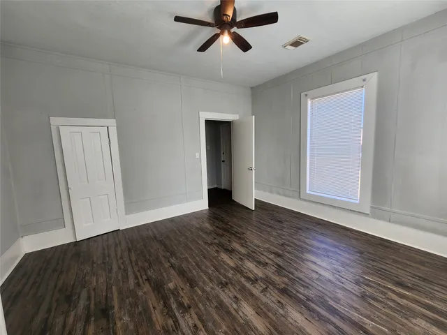 a view of empty room with wooden floor and fan