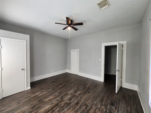 an empty room with wooden floor closet and windows
