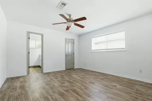 a view of empty room with wooden floor and fan