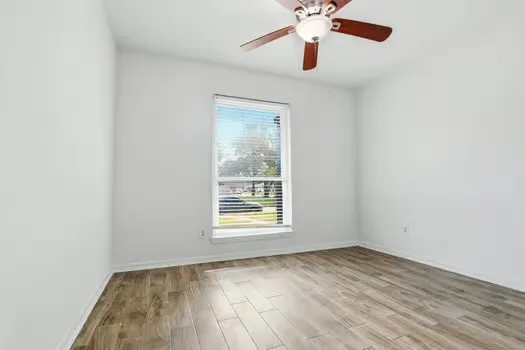an empty room with a window and a ceiling fan