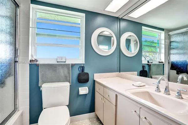 a bathroom with a granite countertop sink mirror toilet and shower