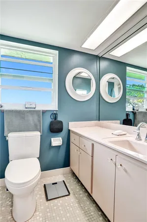 a bathroom with a granite countertop sink a toilet a mirror and a shower